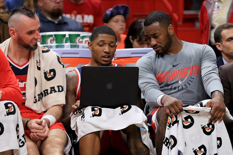 MIAMI, FL - OCTOBER 11: Marcin Gortat #13, Bradley Beal #3, and John Wall #2 of the Washington Wizards look at a laptop during a preseason game against the Miami Heat at American Airlines Arena on October 11, 2017 in Miami, Florida. NOTE TO USER: User expressly acknowledges and agrees that, by downloading and or using this photograph, User is consenting to the terms and conditions of the Getty Images License Agreement. (Photo by Mike Ehrmann/Getty Images)